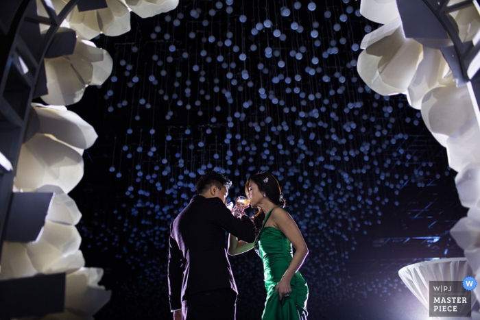 Photo by: <a href="https://www.wpja.com/contests/2015-q4-photography-contest/toastingspeeches/1745596">Daniel Beh - Singapore</a> Singapore bride and groom crossing arms with their drinks at the reception | Asia wedding photo
