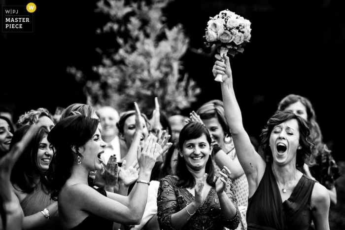 Foto door: <a href="https://www.wpja.com/contests/2015-q4-photography-contest/bouquetgarter-action/1735696"> Luigi Rota - Italië </a> Lecco gasten klappen als een meisje het boeket omhoog houdt Lombardia bruiloft fotojournalistiek