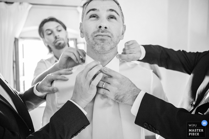 Novio de Venecia recibiendo ayuda para vestirse para la boda | Veneto fotografía de boda