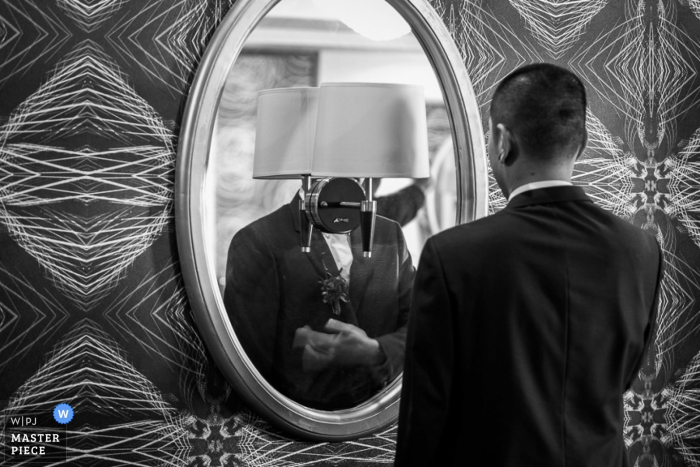 Foto por: <a href="https://www.wpja.com/contests/2015-q4-photography-contest/groom-getting-ready/1734831"> Jianghui Feng - China </a> El novio de Beijing se asegura de que su traje se vea bien en el espejo antes de la ceremonia | China fotoperiodismo de boda