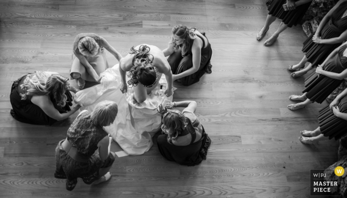 Foto di: <a href="https://www.wpja.com/contests/2015-q4-photography-contest/bride-getting-ready/1730271"> Kent Meireis - Stati Uniti </a> Le damigelle damigelle del Montana aiutano la sposa con il suo abito da sposa | Foto di matrimonio degli Stati Uniti
