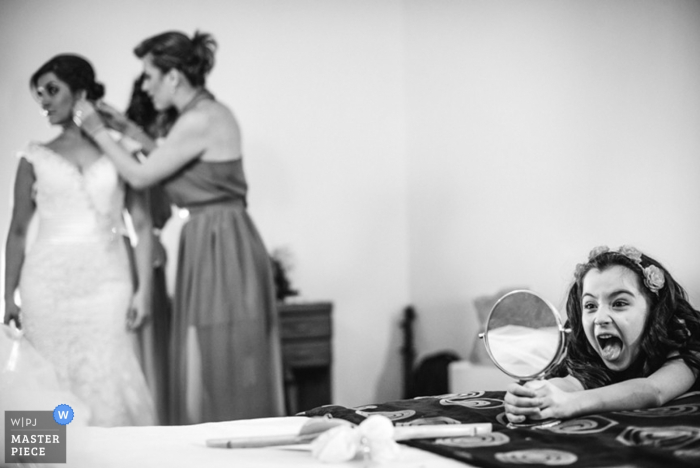 Foto di: <a href="https://www.wpja.com/contests/2015-q4-photography-contest/bride-getting-ready/1738396"> Juan Tamayo - Colombia </a> La bambina si guarda allo specchio mentre la sposa si prepara per il matrimonio
