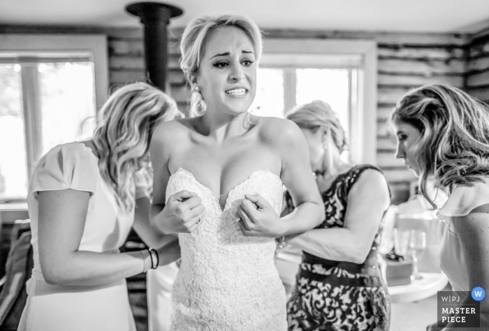Foto por: <a href="https://www.wpja.com/contests/2015-q4-photography-contest/bride-getting-ready/1742411"> Alison MacLean - Estados Unidos </a> Foto en blanco y negro de la novia de Denver que se pone su vestido con algo de ayuda | Fotografía de la boda de colorado