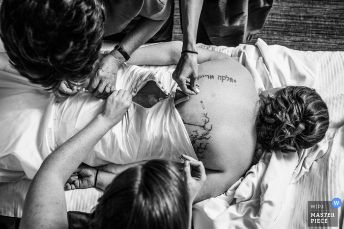 Foto di: <a href="https://www.wpja.com/contests/2015-q4-photography-contest/bride-getting-ready/1757501"> Allison Williams - Stati Uniti </a> Fotografia di matrimonio di Chicago della sposa che viene aiutata nel suo vestito durante la preparazione