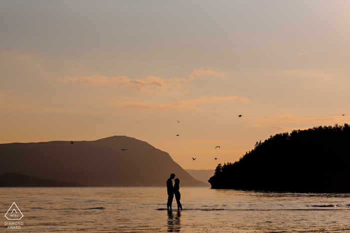 Photo: <a href="https://www.wpja.com/photos/diamond-award-top-wedding-engagement-photographer/2172836"> Curtis Moore - Photographe de mariage au Canada </a> Manitoba Engagement Photography. En pataugeant dans l'eau, un couple s'embrasse au coucher du soleil.
