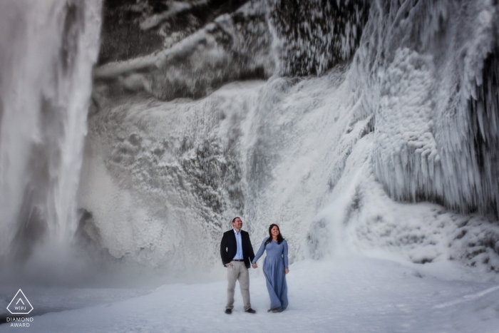 A Maryland couple poses near an ice waterfall during their pre-wedding portrait session A Maryland couple poses during their pre-wedding portrait session by a Baltimore photographer