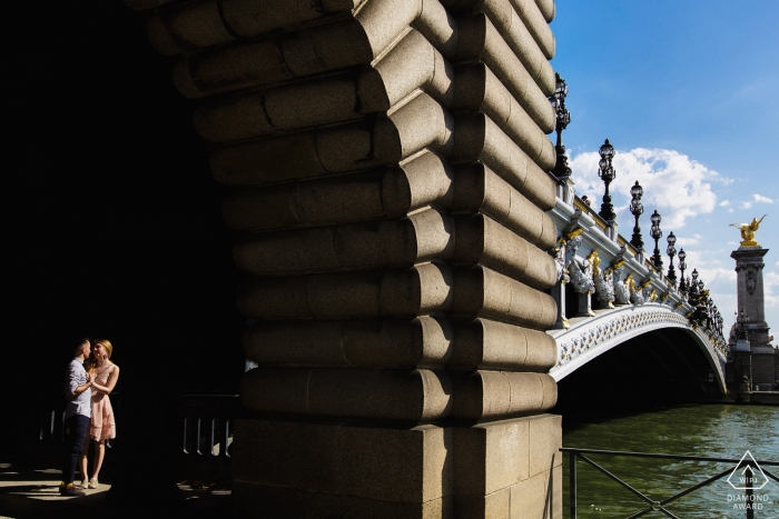 Frankreich-Verlobungsfoto mit einem Paar, das durch die Sonne an der Brücke beleuchtet wird