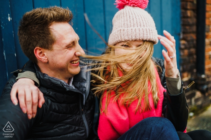 Foto: <a href="https://www.wpja.com/photos/diamond-award-top-wedding-engagement-photographer/2170416"> Rob Dodsworth - Norwich Norfolk England Verlobungsfotograf. Winterpaarporträts mit Jacken und Mützen im kalten Wind.