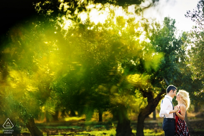 Trapani sesión de compromiso al aire libre en medio de los altos árboles verdes y la luz del sol