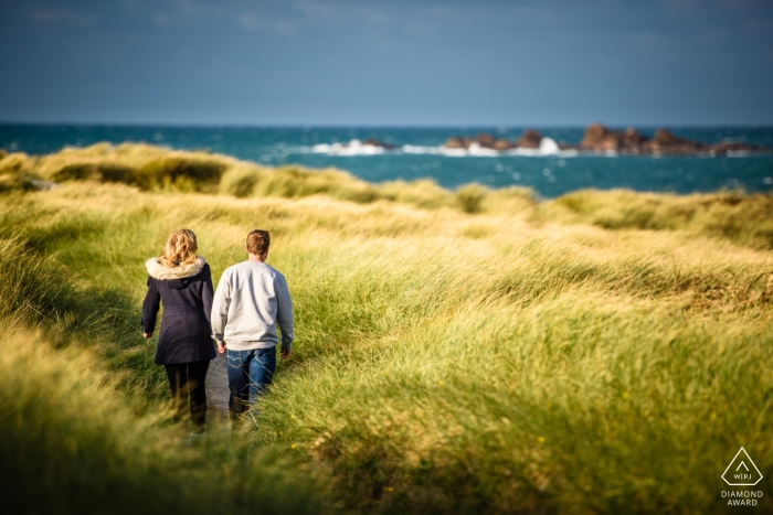 Foto: <a href="https://www.wpja.com/photos/diamond-award-top-wedding-engagement-photographer/2184716"> Nick Despres - Hochzeitsfotograf aus dem Vereinigten Königreich </a> Guernsey Channel Islands paar Portrait Session / ein Paar im hohen Gras in Richtung Strand