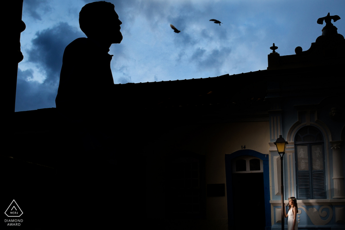 Goiás couple posing in the early evening under birds in the city for some creative prewed portraits Goiás couple posing in the early evening under birds in the city