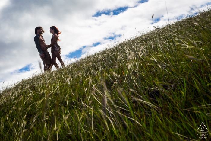 Portraits pré-mariage de Madrid d'un couple dans un champ d'herbe | horizon incliné avec un ciel bleu et des nuages