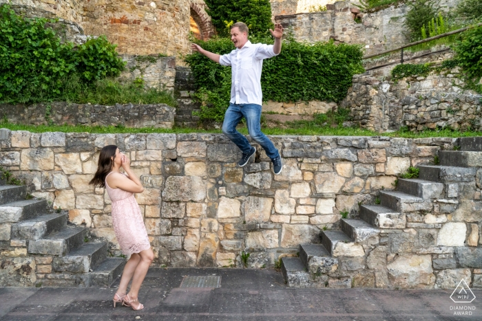 Photo by: <a href="https://www.wpja.com/photos/diamond-award-top-wedding-engagement-photographer/2198821">David Anton - Germany Wedding Photographer</a> Baden-Wurttemberg bride to be watches as her fiancé jumps off a very high stone wall during engagement portrait session