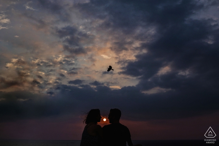 A solo bird flies overhead during this sunset engagement session in Sri Lanka