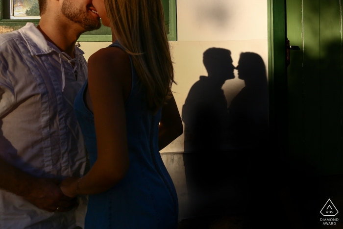 Brazil pre-wedding photo shoot in the afternoon sun throws a shadow on the building of this couple kissing