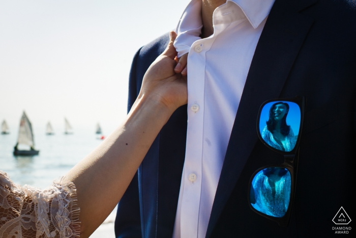 Photo by: <a href="https://www.wpja.com/photos/diamond-award-top-wedding-engagement-photographer/2249176">Vinci Wang - China Wedding Photographer</a> A young woman grabs the collar of her fiancé has she is reflected in the sunglasses hanging from his coat pocket in China