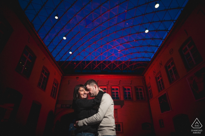 Foto por: <a href="https://www.wpja.com/photos/diamond-award-top-wedding-engagement-photographer/2311006"> Samuel Berthelot - Alzingen Pareja comprometida enamorada del fondo rojo durante su sesión de retratos de bodas en interiores
