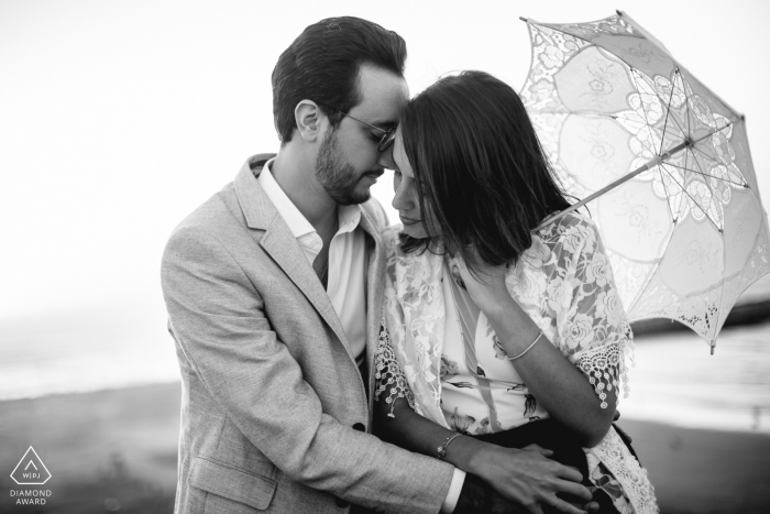 France black and white pre-wedding engagement pictures of a couple hugging with umbrella  | Paris portrait shoot