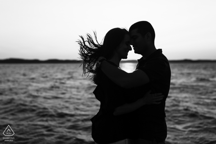 Photos de fiançailles noires et blanches du Portugal d'un couple se profilant à l'océan dans le vent | Séance photo avant le mariage avec le photographe Braga