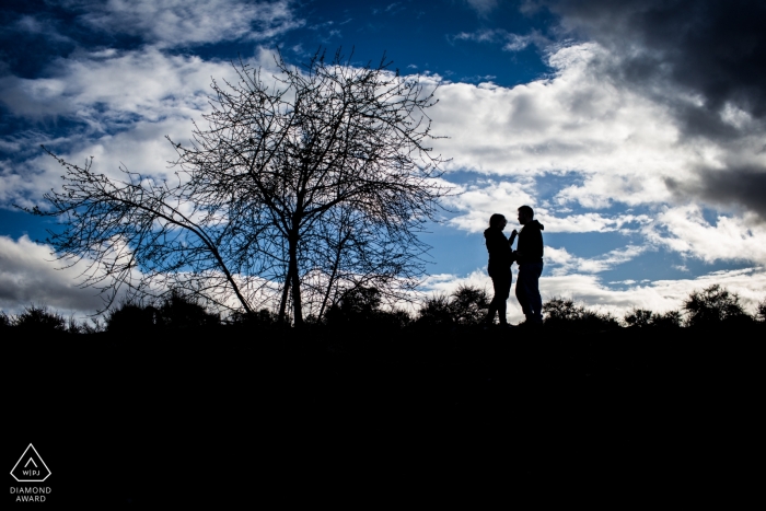 Fotografía de compromiso de boda en madrid con una pareja contra el cielo azul con nubes | Fotografia de españa