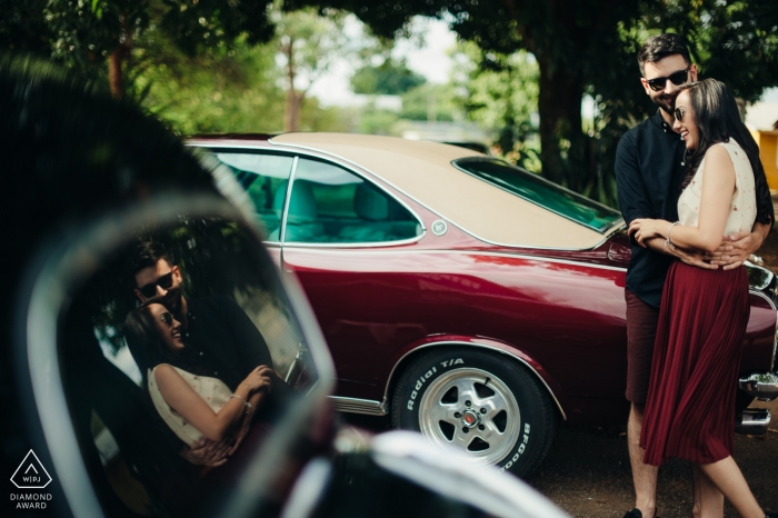 Fotografo di matrimoni di auto hot rod d'epoca | ritratto di fidanzamento di una coppia riflessa nel vetro auto | Foto pre-matrimonio di Brasilia