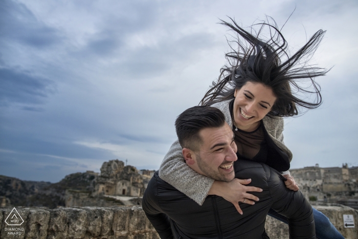 Photo by: <a href="https://www.wpja.com/photos/diamond-award-top-wedding-engagement-photographer/2340031">Pasquale Minniti - Reggio Calabria A Calabria engagement photo shoot session of a couple piggy back in the wind | Reggio Calabria wedding photographer