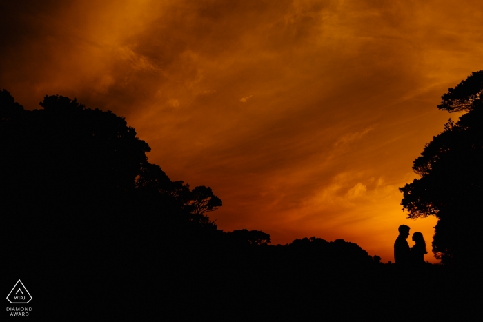 Brazil engagement pictures of a couple silhouetted with trees and orange sky with clouds  | Canion Fortaleza photographer pre-wedding photo shoot session