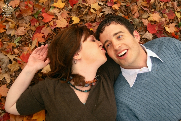 Atlanta wedding engagement portrait of a couple on their backs in fall colored leaves  | Georgia pre-wedding photographer session