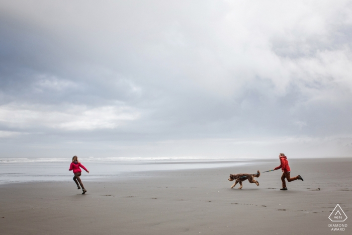 Baltimore: photos d'un couple en train de courir sur la plage avec un chien, par un photographe de mariage haut du Maryland