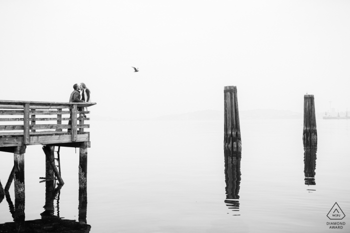 Seattle couple on pier with water reflections during engagement shoot