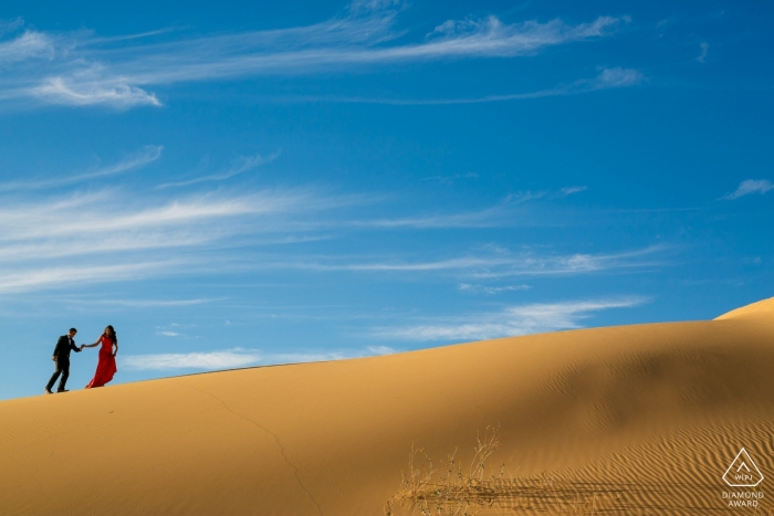 Pareja caminando por las dunas de arena de Glamis para una sesión de compromiso en el desierto