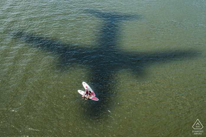 SUP wedding engagement photography in District Of Columbia with the shadow of an airplane on the water