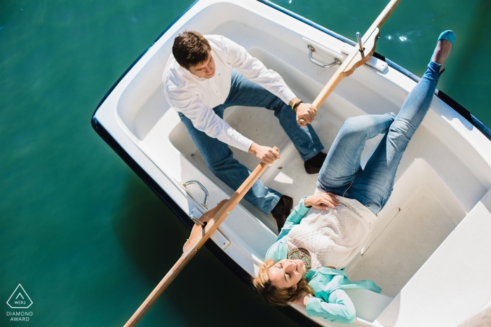 A Spain engaged couple pose in a row boat for their pre-wedding portraits for Madrid engagement photographer