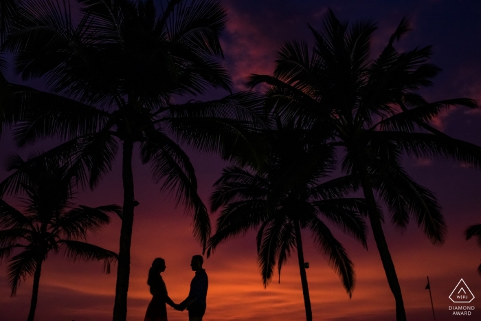 La fotografia di fidanzamento di prewedding spara a Goa con un cielo rosso e palme scure