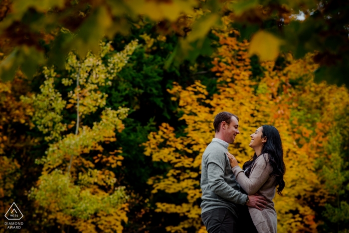 Engaged couple cuddle in fall colours during their engagement photography session | Nelson BC Wedding Photographer