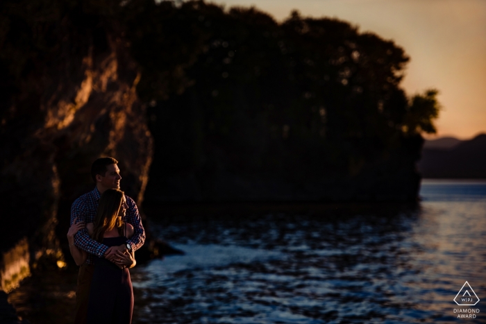 Verlobungsfoto aus Vermont, auf dem sich ein Paar bei Sonnenuntergang am Strand umarmt