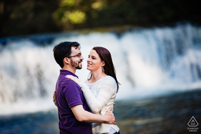 A young North Carolina newly engaged couple in the face of the powerful, solid wall of a rushing waterfall