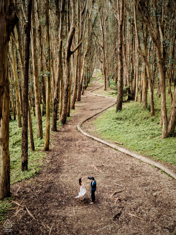 Um casal da Califórnia está dançando emoldurado pela trilha sinuosa de troncos na floresta