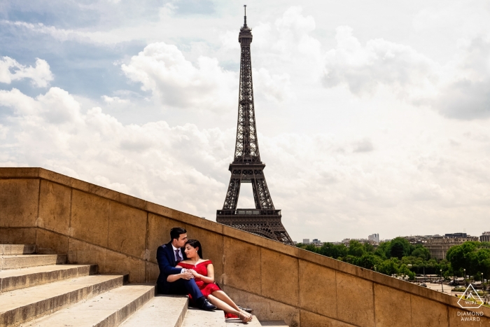 Um casal apaixonado pela cidade de Paris sentados juntos nos degraus com vista para uma torre