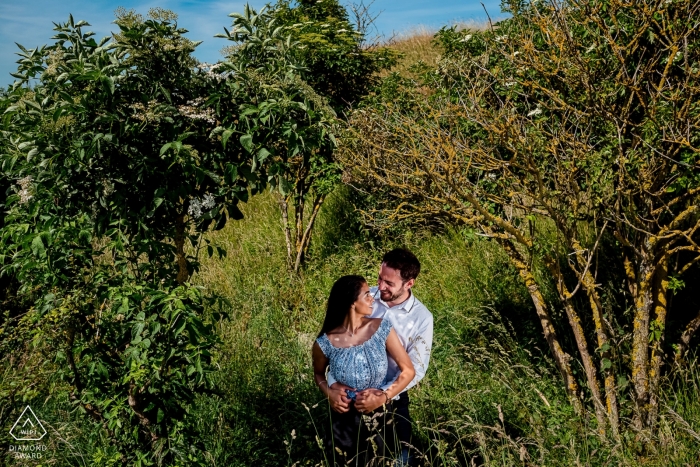 The romantic Paris engaged couple is framed by lush green leaves