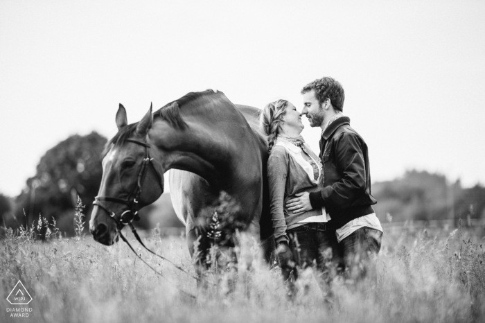 The Hessen couple embrace against a horse in a pasture