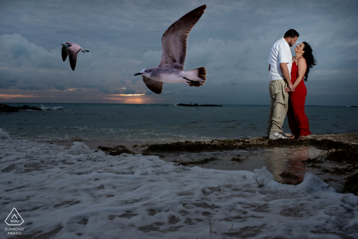 Coppia di fidanzati della Florida, con schiuma di mare che si lava a riva e gabbiani