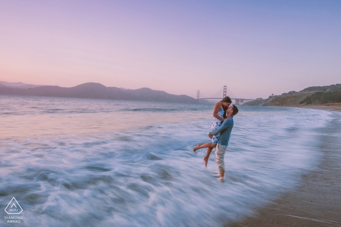 Retrato da Califórnia de um casal na praia, com a velocidade lenta do obturador desfocando a água em movimento