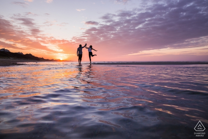 Danse exubérante d'un couple du Massachusetts au coucher du soleil, la femme levant la jambe