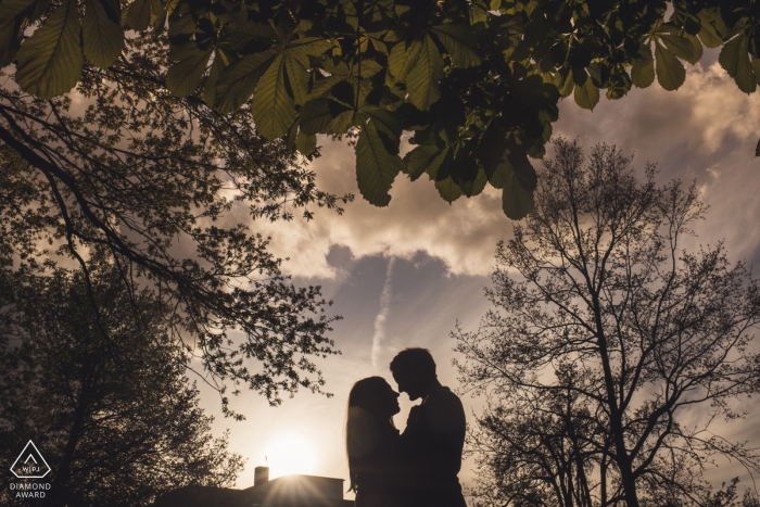 A London engaged couple is framed by trees and clouds against the sky