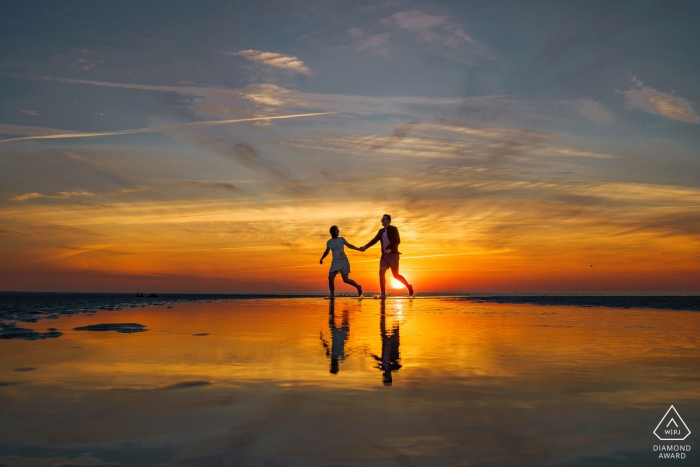 Pareja comprometida de Massachusetts corriendo sobre los reflejos de los colores del atardecer