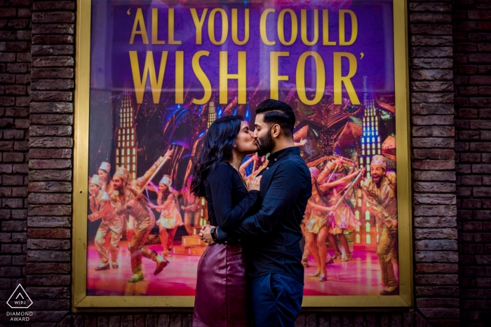 A playful Dubai UAE couple in a modern, urban setting with a Bollywood poster