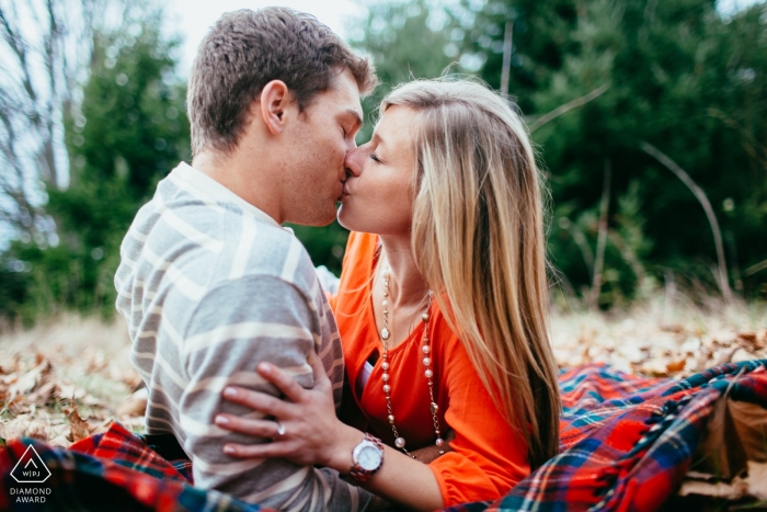 Young Washington couple kissing on a picnic blanket in the golden hues of autumn