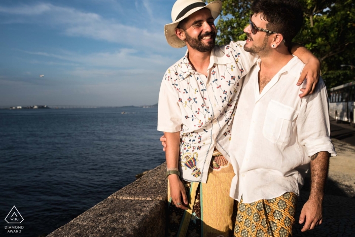 Un couple fiancé a été photographié debout devant un mur de pierre à Rio de Janeiro, bras autour des épaules, surplombant la mer