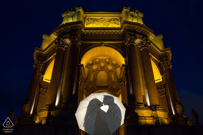 The California couple's embraced silhouettes are visible through the translucent white umbrella